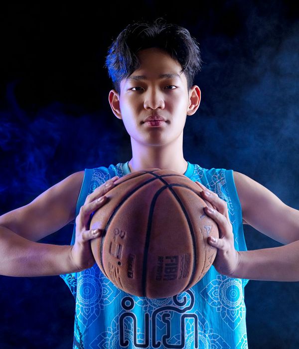 Man performing a dynamic bodyweight exercise in a dark studio.